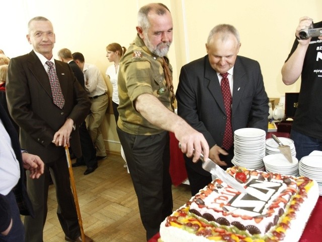Dariusz Boguski (z nożem) kroi urodzinowy tort. Na spotkanie założył mundur "baczyńskich"