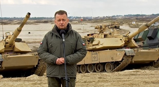 Minister Mariusz Błaszczak na tle czołgów Abrams