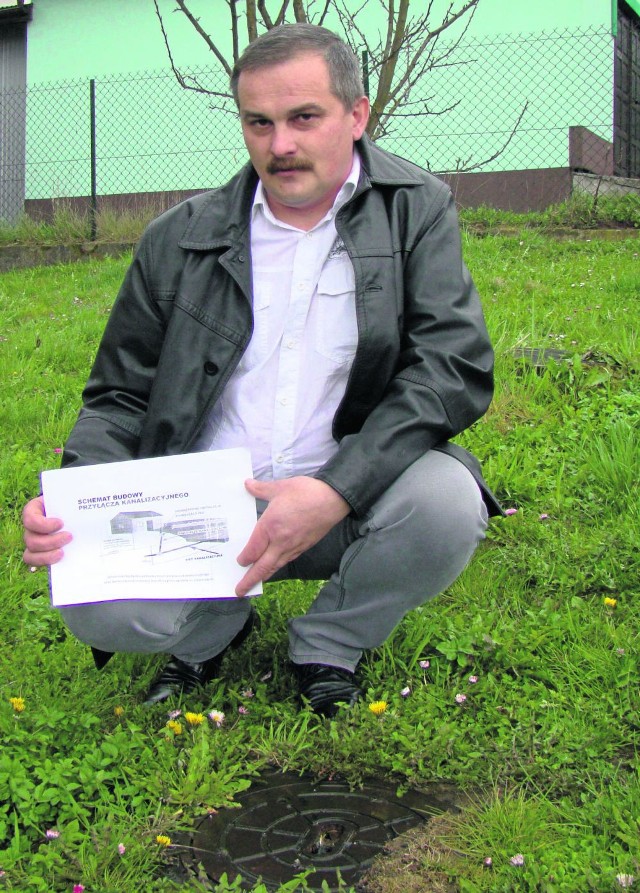Roman Sermak przy studzience kanalizacyjnej koło jego domu. Uważa, że zapłacić ma gmina