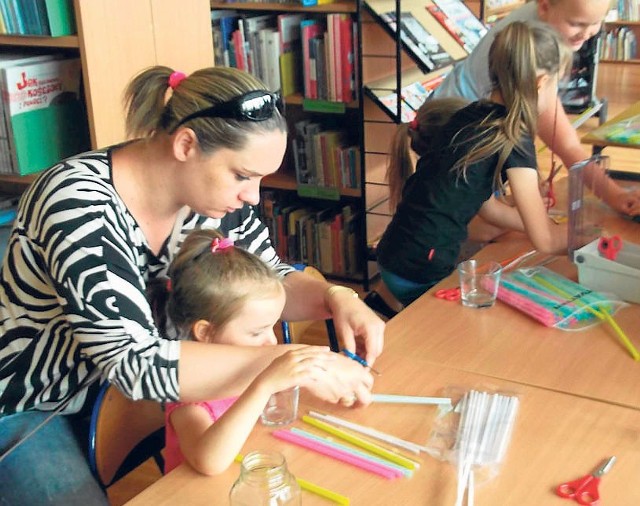 Najmłodszym uczestnikom wakacyjnych zajęć plastycznych „Z kolorami w bibliotece” w realizowaniu artystycznych pomysłów chętnie pomagają mamy