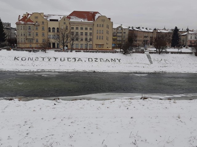 Napis "Konstytycja, dzbany" na skarpie Sanu w Przemyślu, przeciw okien biur Prawa i Sprawiedliwości.