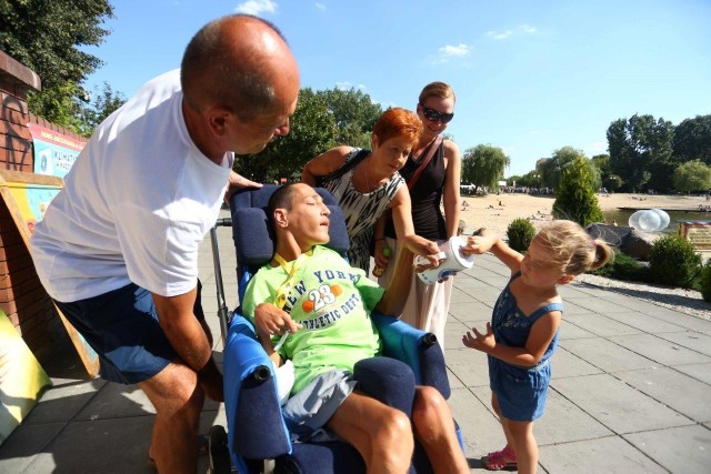 3,5-letnia Zosia Maj wrzuca do puszki Andrzeja Kunowskeigo pieniądze dla chorego Szymona. Towarzyszą jej od prawej: mama Kalina Maj, Joanna Kunowska ze Stowarzyszenia "Podzielmy się uśmiechem&#8221; oraz Sławomir Kunowski.