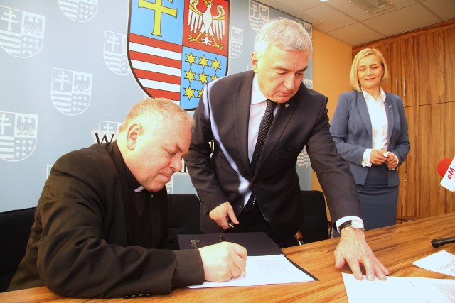 Dyrektor Caritas Diecezji Kieleckiej ksiądz Stanisław Słowik podpisuje umowę na dofinansowanie z marszałkiem województwa, Andrzejem Bętkowskim.