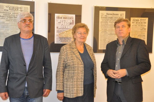 Dyrektor biblioteki Dariusz Kowalczyk (z prawej) z właścicielką czasopism Leokadią Szmit oraz radnym i sołtysem Rogowa Markiem Kozerawskim na tle wystawionych wojennych gazet.