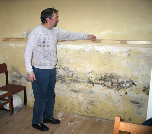 Jerzy Łakomski, wiceprezes Stowarzyszenia Wspierania Bezrobotnych, które także korzysta z pomieszczeń, pokazuje odpadające kawałki zawilgoconej ściany. 