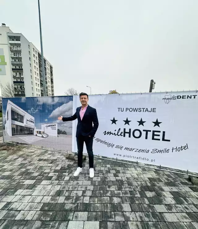 Doktor Piotr Trafidło przy banerze na ogrodzeniu budowy Smile Hotelu