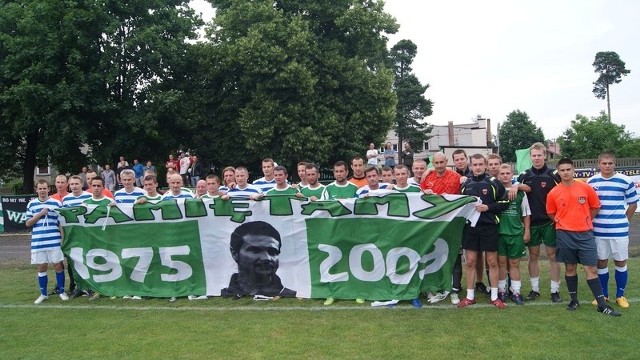 Pamiątkowe zdjęcie zawodników obu drużyn na tle flagi ufundowanej przez kibiców Prochu Pionki.