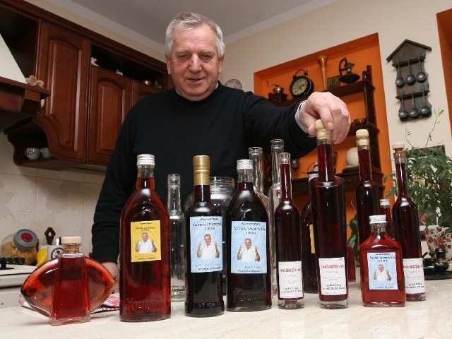 Wójt Tadeusz Tkaczyk prezentuje nalewki, każda butelka z etykietką