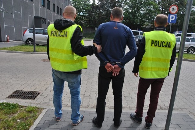 Policjanci konwojują 38-letniego mężczyznę, który podpalił 56-letniego bezdomnego