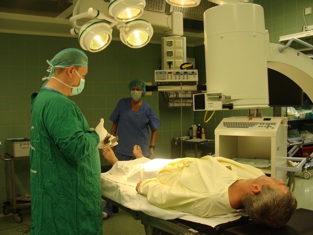 Jacek Dworak wykonuje zabieg urologiczny z pomocą ramienia C oraz lasera. Asystują mu instrumentariuszki; Teresa Pałac i Barbara Okłotowicz.