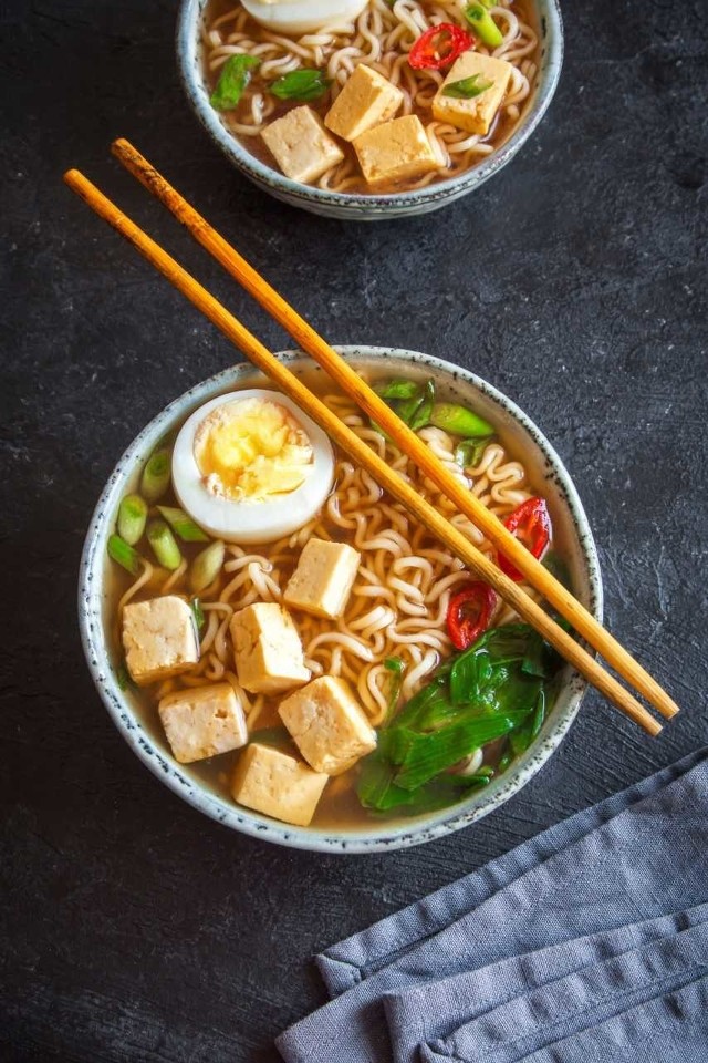 Ramen - sycąca zupa na chłodne dni - do Japonii przywędrował z Chin i różni się od tradycyjnych japońskich zup tym, że zawiera mięso, a nie głównie ryby i warzywa. Polecany jest zwłaszcza na chłodne pory roku, bo jest zupą gęstą, która syci i rozgrzewa. Nic dziwnego, że stała się ona bardzo popularna również u nas, bo my Polacy lubimy przecież zupy nie wodniste, ale bardziej treściwe. A ramen to nic innego jak treściwy rosół, przygotowany na mięsie wieprzowym lub drobiowym. Za jego charakterystyczny smak odpowiadają również bardzo precyzyjnie dobrane warzywa i przyprawy oraz makaron, najlepiej typu azjatyckiego - udon, chow mein, opcjonalne także soba. Na tle innych japońskich zup ramen wyróżnia się tym, że zawiera mięso, a nie wyłącznie ryby oraz warzywa. Jakie składniki najczęściej dodawane są do ramenu? Kapusta pekińska, szczypiorek, cebula, pędy bambusa, por, wodorosty, chili, czosnek, imbir, tofu, cienkie plastry mięsa oraz jajko ugotowane na twardo. Część warzyw kroi się w drobne słupki i dodaje do miseczek z makaronem tuż przed wlaniem wywaru, dzięki czemu są one chrupkie i zachowują dużo cennych składników odżywczych. Ugotowanie domowego ramenu wcale nie jest zadaniem trudnym, zwłaszcza jeśli na początek wybierzemy prostą i szybką w przygotowaniu recepturę. Każdy element zupy powinien być jednak przygotowany z dbałością o najmniejszy szczegół, jak na japońską kuchnię przystało.  Ramen z kaczki z serem Składniki:ok. 3,5 l wody1 pęczek włoszczyzny4 udka z kaczki3 ząbki czosnku2-3 cząstki świeżego imbirusól i sos sojowy do smaku250 g makaronu chińskiego1 pęczek szalotki ze szczypiorkiem150 g sera morskiego 1 papryczka chilli3 jajka ugotowane na twardoWłoszczyznę obrać, udka z kaczki umyć i wszystko włożyć do garnka, zalać zimną wodą. Doprawić solą, sosem sojowym i gotować na bardzo wolnym ogniu do momentu, aż mięso będzie miękkie. W połowie gotowania dodać obrany i grubo pokrojony czosnek oraz imbir. Mięso oddzielić od kości, pokroić razem z warzywami w cząstki i wyłożyć do miseczek. Wyłożyć również świeżo ugotowany i gorący makaron, grubo pokrojoną szalotkę ze szczypiorem i cienkie plasterki papryki chilli. W każdej miseczce umieścić po połówce jajka. Całość zalać wrzącym rosołem. Na koniec do miseczek z rosołem włożyć pokrojony w grubą kostkę ser morski.(msm-monki.pl)Ramen z kurczakaSkładniki:1 filet z kurczaka3 marchewki1 por (biała część)1 kapusta pekińskamakaron wstążki2 papryczki chilliduża cebula1 dymka1/2 selerakiełki z fasoli mung4 ząbki czosnkuszczypta chilli, pieprz i sól do smakuDo posolonej zimnej wody - ok. 2-3 l włożyć pierś i doprowadzić do wrzenia. Gotować na małym ogniu ok. 2 godzin. Cebulę przekroić na pół i opalić do zwęglenia się np. na patelni bez tłuszczu. Wrzucić ją do gotującego się wywaru razem z selerem, posiekanym czosnkiem i papryczką chilli i gotować 15 min. Pod koniec gotowania wrzucić posiekaną kapustę, kiełki i łyżeczkę pieprzu ziarnistego. Dodać pokrojoną marchewkę i doprawić solą oraz sproszkowanym chilli. Ugotować makaron zgodnie z instrukcją na opakowaniu. Pierś z kurczaka wyjąć, pokroić w poprzek na małe paski i lekko obsmażyć. Do miseczek nałożyć makaron, trochę pasków z kurczaka i zalać wywarem z warzywami. Posiekać dymkę i por i wrzucić do miseczki.(www.winiary.pl)