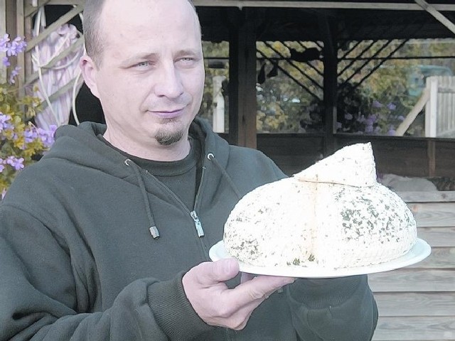 Marcin Wojnowski z Qzko z dumą pokazuje kozi ser karolacki z ziołami