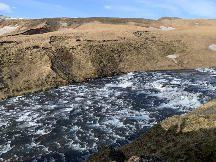 Rwący nurt rzeki zmieniającej się w wodospad Skógafoss