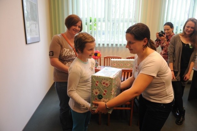Anna Świtała, wolontariuszka fundacji "Mam Marzenie&#8221; i studentka fizjoterapii PMWSZ w Opolu, wręcza prezent dla Klaudii. Dziewczynka czuła się na tyle dobrze, że mogła przyjechać z rodziną i odebrać go na uczelni.