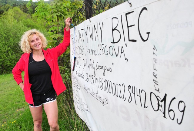 Izabela Zatorska-Pleskacz przy białej płachcie, na której składają swoje podpisy wszyscy biegacze startujący w akcji charytatywnej