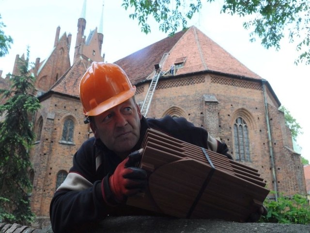 Arkadiusz Markiewicz przenosi dachówki przy pomocy specjalnego podnośnika