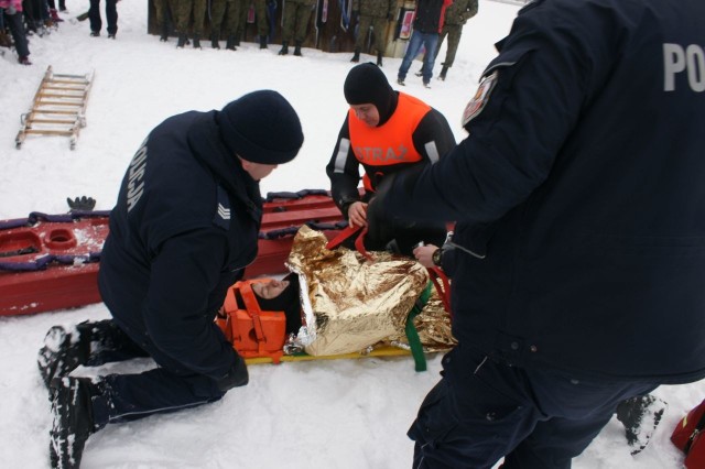 Policjanci posiadający przeszkolenie z zakresu ratownictwa lodowego pokazywali sposób ratowania poszkodowanego przy pomocy rzutki ratunkowej oraz boi „SP”.