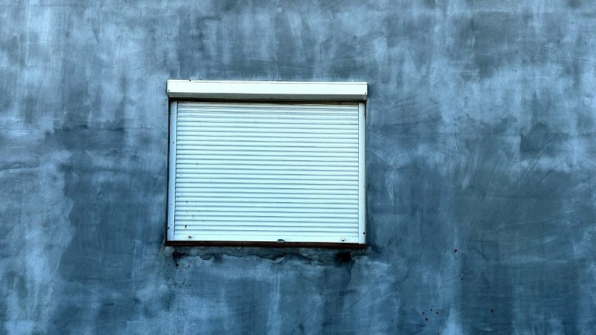 Niewykończona fasada, w oknach opuszone rolety, a podwórze...
