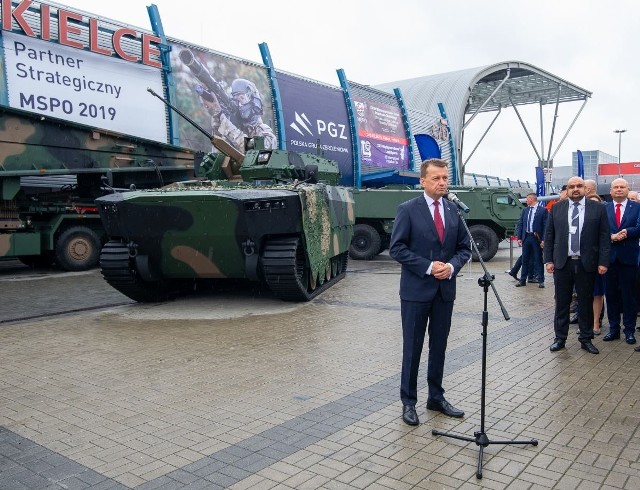 Minister obrony Mariusz Błaszczak na salonie obronnym przy modelu bojowego wozu piechoty z Huty Stalowa Wola