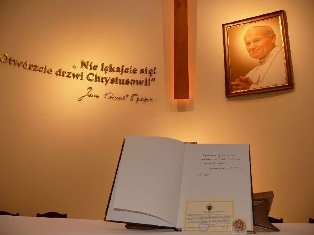 Relikwie papieskie i księga pamiątkowa na tle ołtarza głównego.