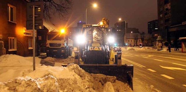 Koparkoładowarki ładują śnieg na wywrotki.