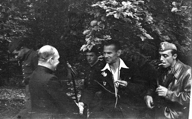 Porucznik „Nurt” Eugeniusz Kaszyński (w środku) wita „Księdza Robaka” Mariana Majewskiego przed polową mszą na Wykusie 12 września 1943 roku. Obok z papierosem porucznik „Habdank” Jerzy Stefanowski.