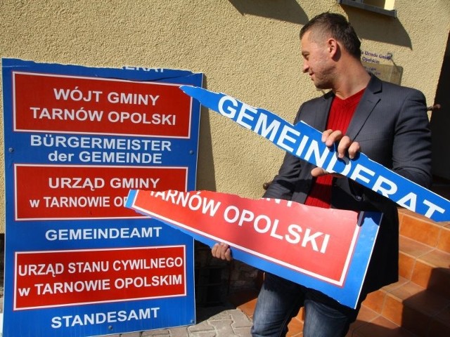 Piotr Koziol, zastępca wójta Tarnowa Opolskiego, pokazuje zniszczoną tablicę.