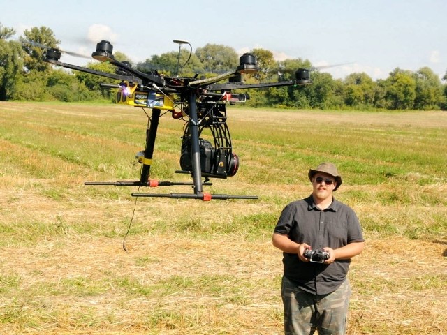 Michał Pisz, archeolog, pilotuje drona robiącego zdjęcia.