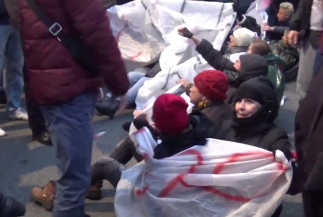 Kobiety usiadły na trasie marszu, trzymając transparent "Faszyzm stop".