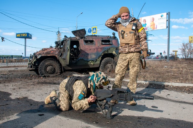 Ukraińscy żołnierze na tle zniszczonego rosyjskiego pojazdu wojskowego