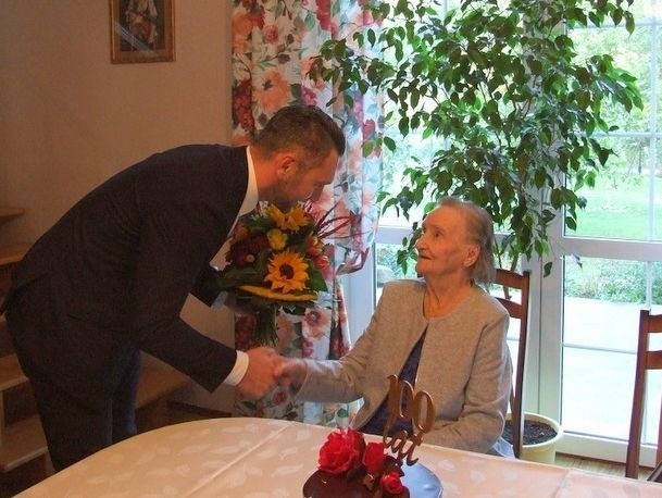 Kwiaty i gratulacje stuletniej Mariannie Kurzynie składa wójt pysznickiej gminy Łukasz Bajgierowicz