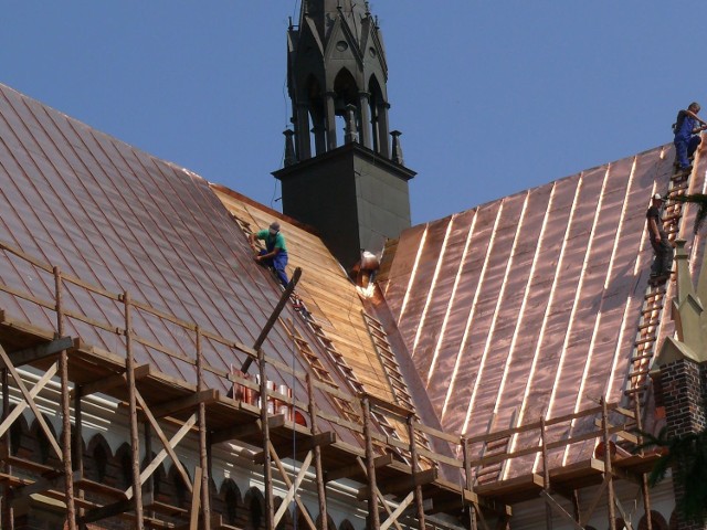 Prace przy układaniu miedzianej blachy na dachu kościoła Matki Bożej Szkaplerznej.