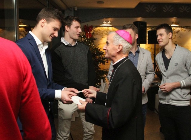 Biskup Marian Florczyk łamie się opłatkiem z Bartoszem Bućko, przyjmującym drużyny Effectora.