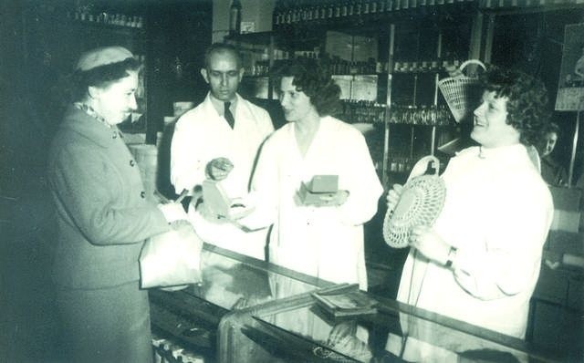 Ta klientka z pewnością nie może narzekać na obsługę w drogerii na rogu Gdańskiej i Świętojańskiej. W dokonaniu wyboru pomagają jej Zygmunt Raczyński oraz dwie ekspedientki. Kobieta w środku  - pani Aneta - została późnej kierowniczką drogerii - 1959 rok.