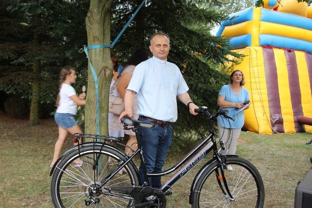 Ksiądz Krzysztof Sieczka, proboszcz parafii świętego Rocha w Mroczkowie prezentuje główną nagrodę loterii, rower. Wylosowała go pani Katarzyna Bernatek.