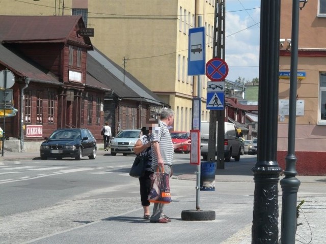 Oczekujący na autobus mają tylko słupek, który z pewnością cienia nie daje.