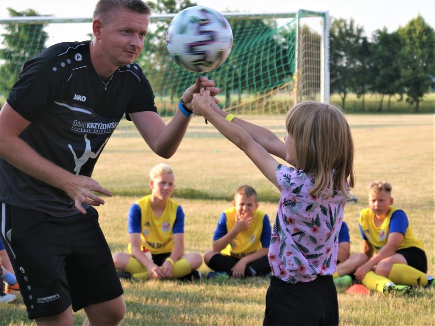 Dawid Krzyżowski pomaga dziewczynce przy triku z piłką