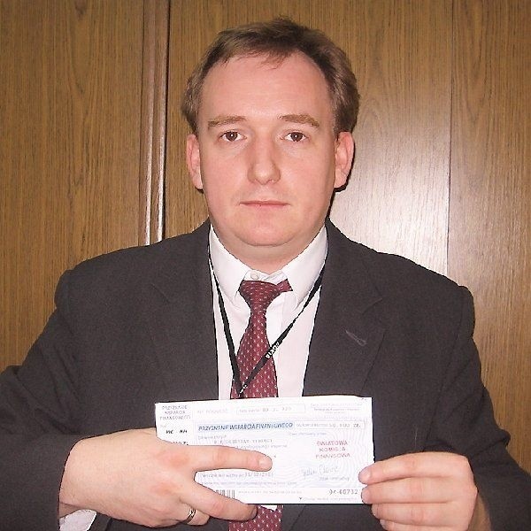 Marcin Pawlak prezentuje niby-czek ze  "Światowej Komisji Finansowej" z rzekomym  wsparciem w wysokości 50 tys. złotych.