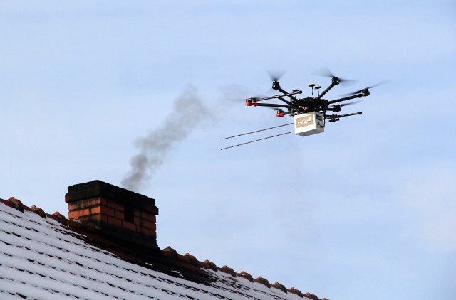 Podlatujący do komina dron pobiera próbkę dymu.