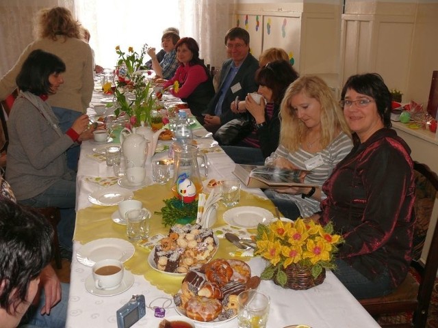 Zagraniczni goście w przedszkolu przy stole z wielkanocnymi przysmakami.