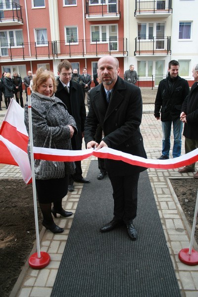 Dywan na chodniku, wstęga przed głównym wejściem i burmistrz Białogardu Krzysztof Bagiński, który przeciął wstęgę.