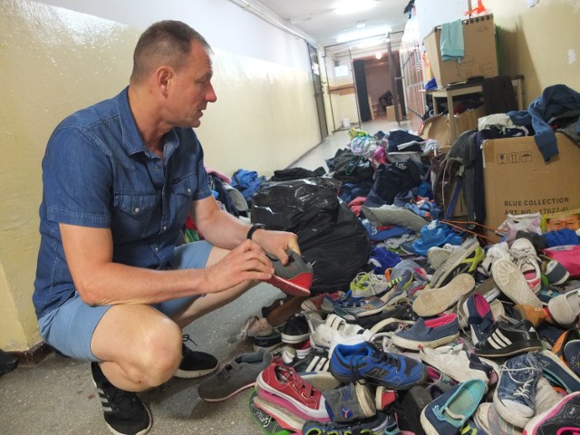 Dyrektor Mirosław Śnigórski i stos zgubionych ubrań oraz butów.