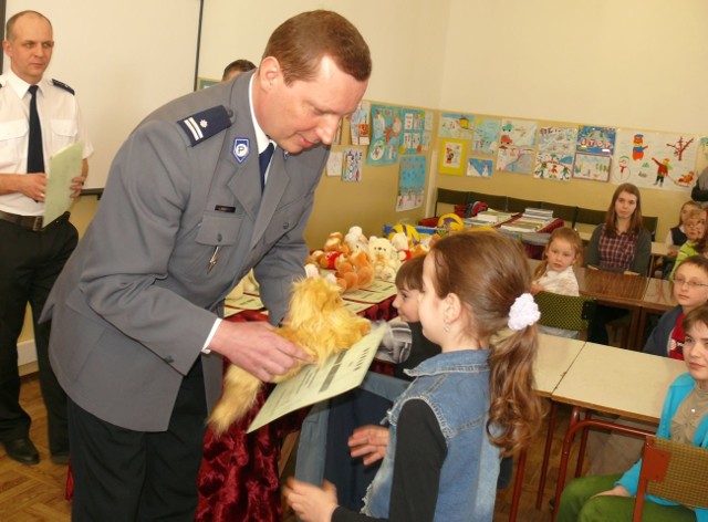 Zastępca komendanta Lucjan Maczkowski wręcza nagrody dzieciom.