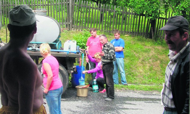 Mieszkańcy z butelkami i miskami czekają na beczkowóz w wyznaczonych miejscach