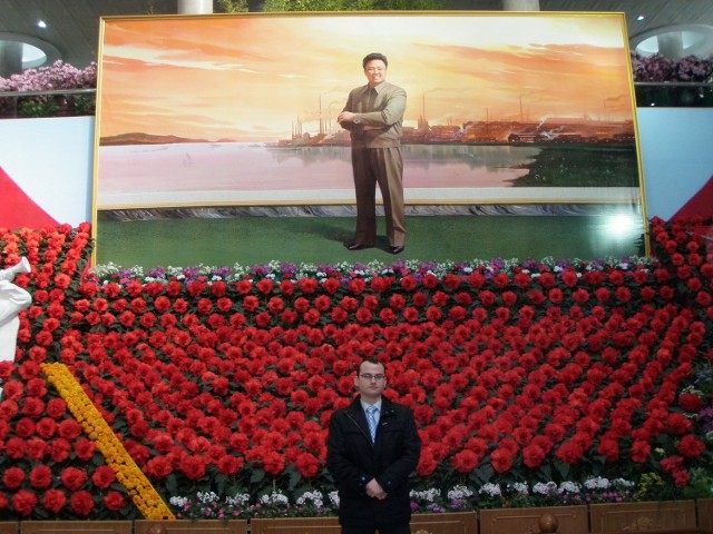 Andrzej Bober, w tle plakat z wizerunkiem Kim Dzong Ila
