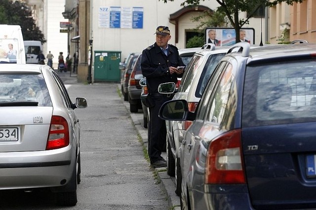 Strażnik Waldemar Sobków sprawdza samochody zaparkowane przy ul. Piekarskiej