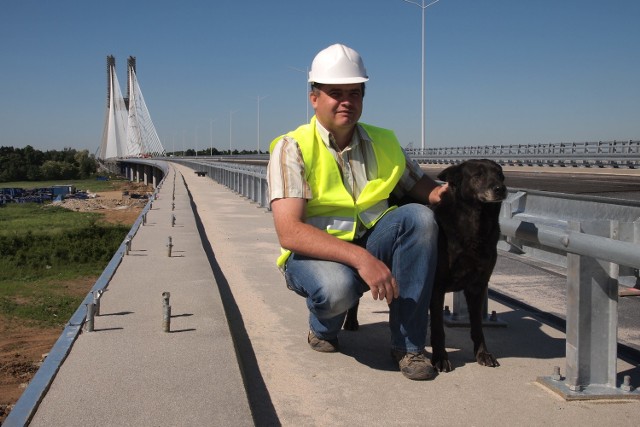 Grzegorz Dechnik na tle mostu na Rędzinie, na zdjęciu z Sonią - pupilką budowlańców