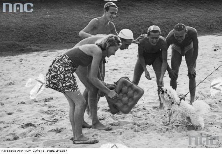 Pięć osób podczas zabawy z psem na plaży nad Wisłą (1940)....