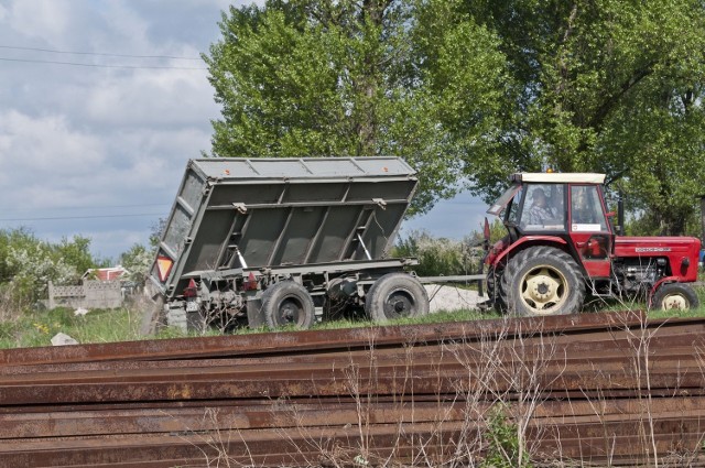 Należący do urzędu gminy traktor wywala gruz na tory.