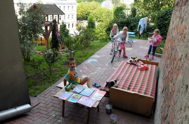 Kolorowy plac zabaw i zielona skarpa przed blokiem, przyciągają dzieci z całej ulicy